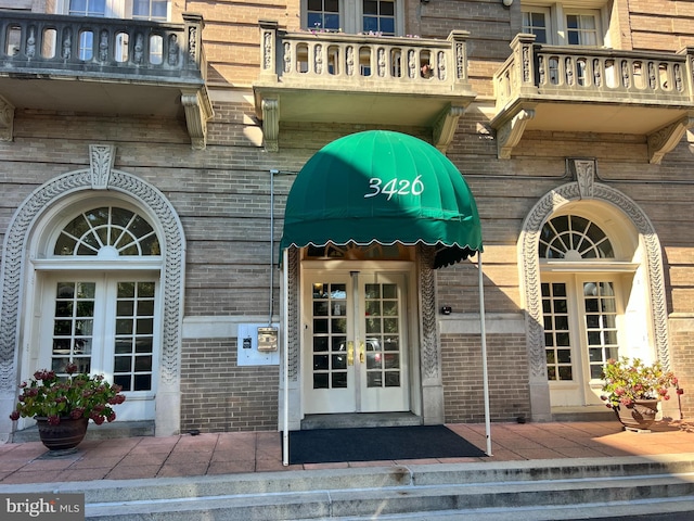 view of exterior entry featuring french doors and a balcony