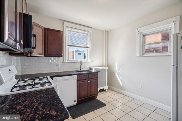 kitchen featuring backsplash, sink, light tile patterned flooring, and white appliances