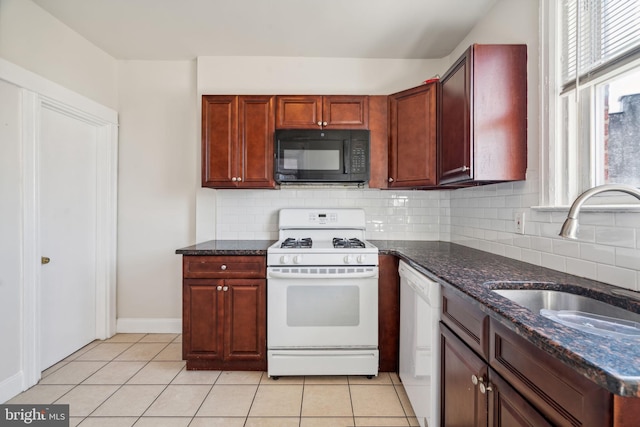 kitchen with white appliances, light tile patterned flooring, sink, dark stone counters, and decorative backsplash