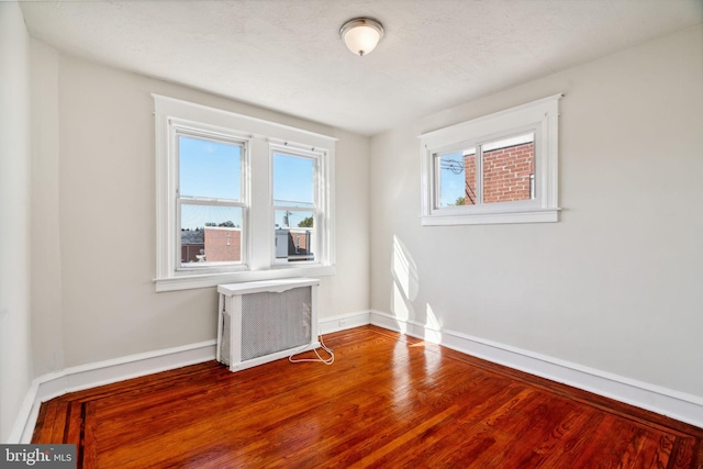 spare room with a textured ceiling, radiator heating unit, and wood-type flooring