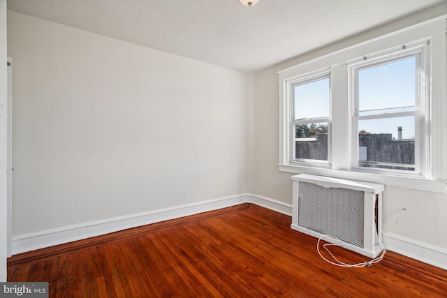 unfurnished room with an AC wall unit and hardwood / wood-style flooring