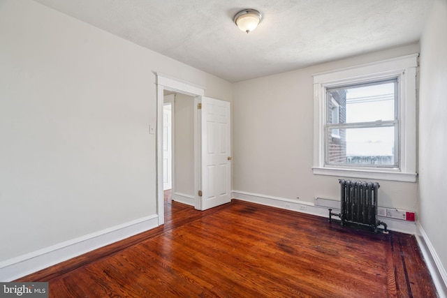 unfurnished room with dark wood-type flooring, a textured ceiling, and radiator heating unit