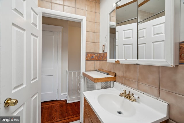 bathroom featuring vanity, hardwood / wood-style floors, tasteful backsplash, and tile walls