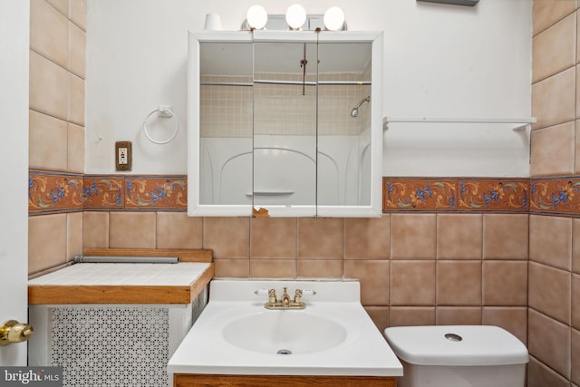 bathroom featuring tile walls, vanity, tiled shower, and toilet