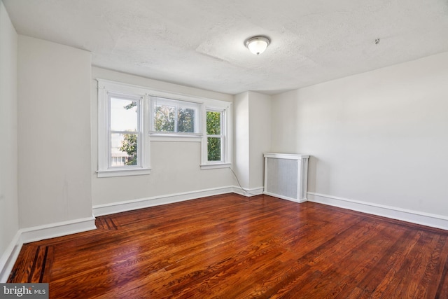 empty room with wood-type flooring and a textured ceiling