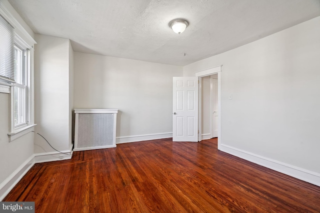 unfurnished room with a textured ceiling and dark hardwood / wood-style flooring