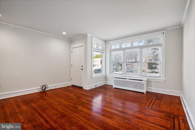 empty room with hardwood / wood-style floors, crown molding, and radiator