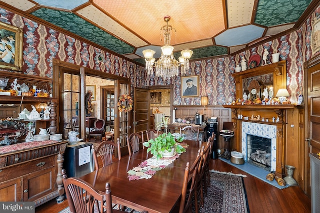 dining room featuring an inviting chandelier, ornamental molding, a tile fireplace, and dark hardwood / wood-style flooring