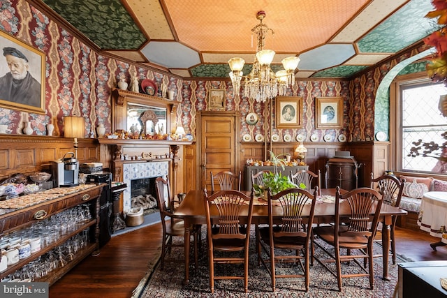 dining area with ornamental molding, a tiled fireplace, dark hardwood / wood-style floors, and an inviting chandelier