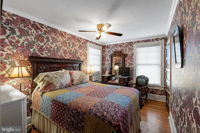 bedroom with ceiling fan, ornamental molding, multiple windows, and hardwood / wood-style floors