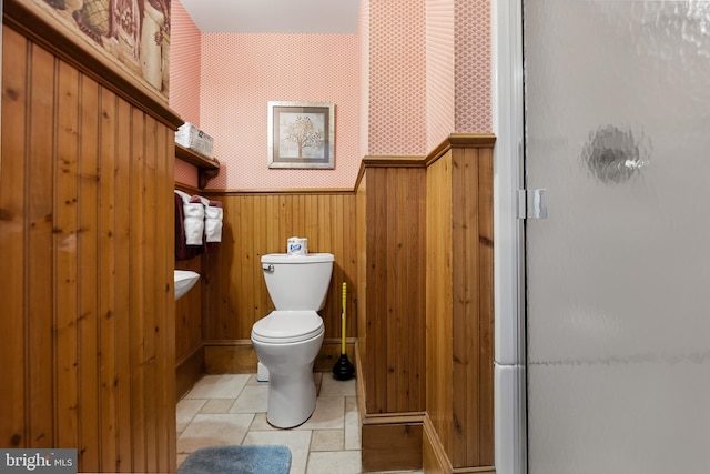 bathroom featuring toilet, wooden walls, and an enclosed shower