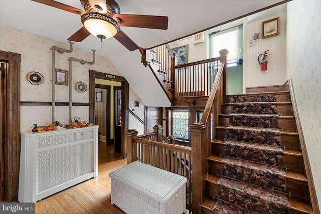 stairs featuring radiator, wood-type flooring, and ceiling fan