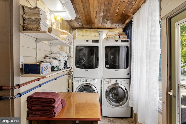 clothes washing area with stacked washer and dryer and wooden ceiling