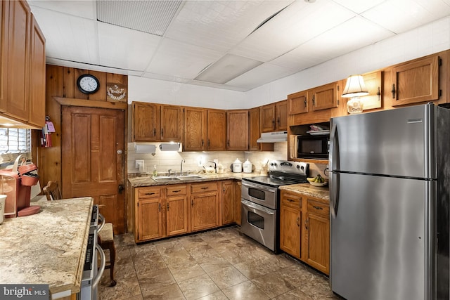 kitchen featuring light stone countertops, stainless steel appliances, decorative backsplash, and sink