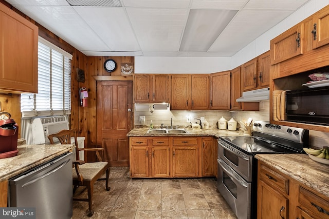 kitchen with backsplash, appliances with stainless steel finishes, sink, and wooden walls