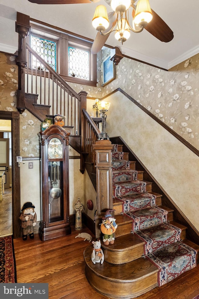 stairway featuring crown molding, wood-type flooring, and an inviting chandelier