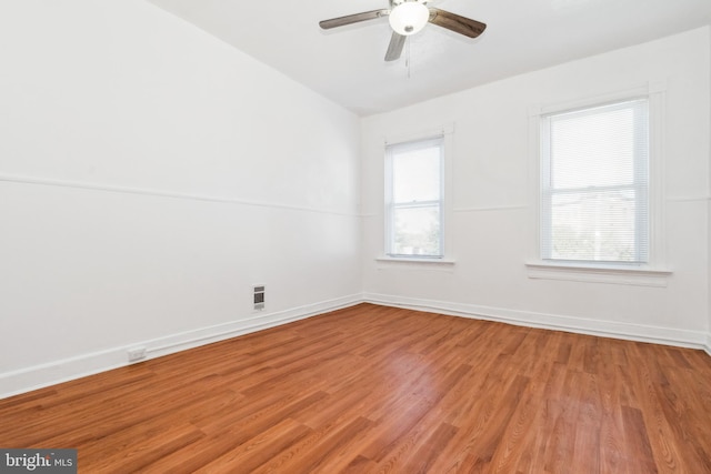 empty room featuring light hardwood / wood-style flooring, a healthy amount of sunlight, vaulted ceiling, and ceiling fan