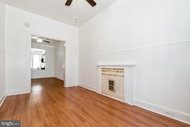 unfurnished living room with lofted ceiling, a fireplace, hardwood / wood-style flooring, and ceiling fan