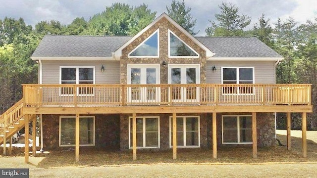 back of property featuring stone siding, a deck, and stairs