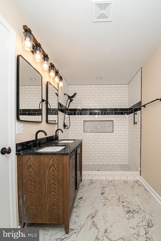 bathroom with visible vents, marble finish floor, vanity, and a tile shower