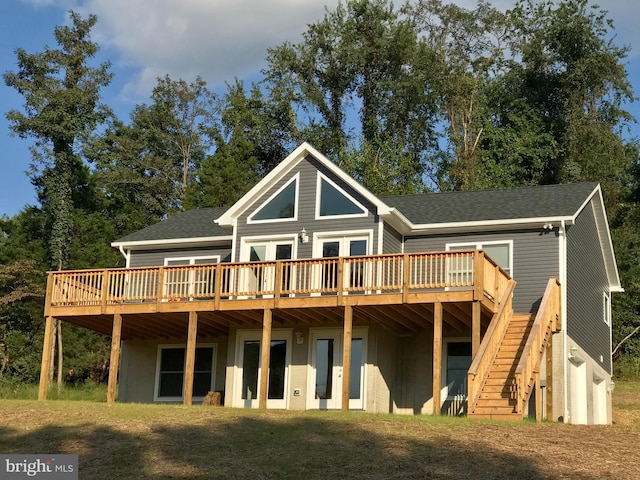 back of property featuring roof with shingles, stairs, and a deck