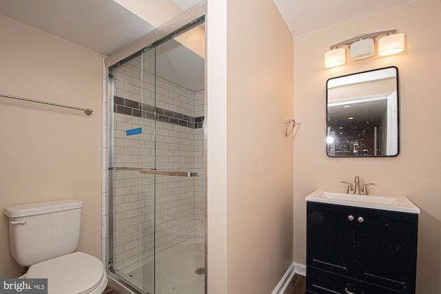 bathroom featuring a shower with door, vanity, and toilet