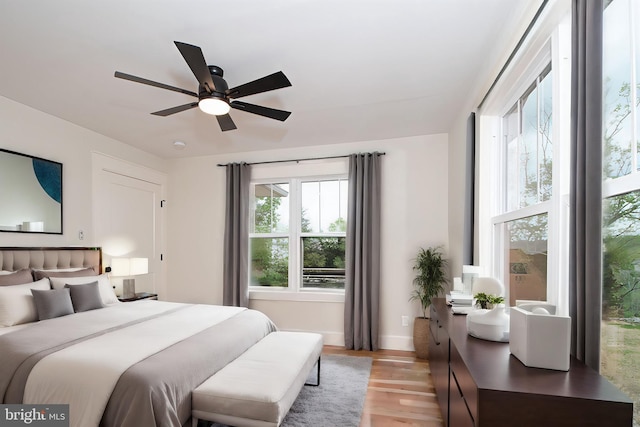 bedroom with baseboards, a ceiling fan, and light wood-type flooring