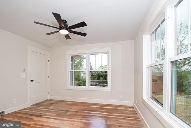 empty room featuring ceiling fan, plenty of natural light, and light wood-type flooring