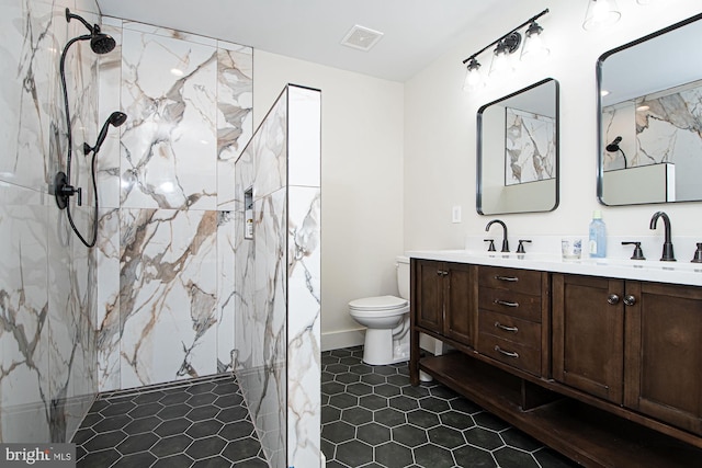 bathroom featuring vanity, toilet, tile patterned floors, and tiled shower