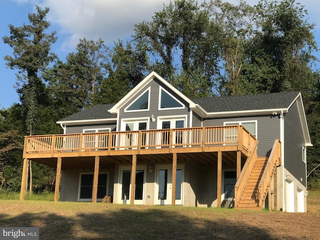 back of house with roof with shingles, stairs, and a deck