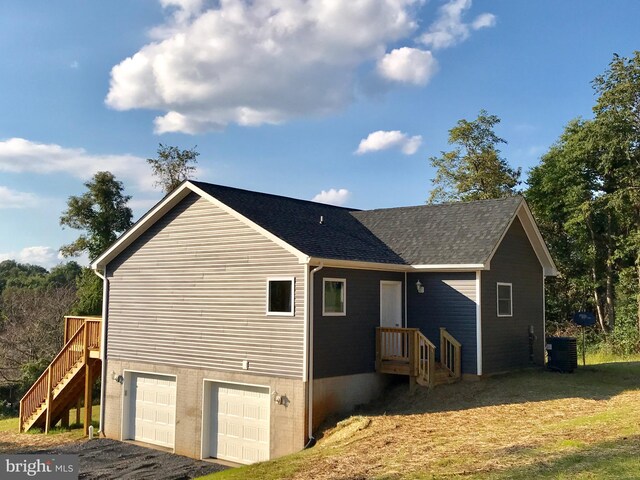 view of side of property with a garage, roof with shingles, stairway, and driveway