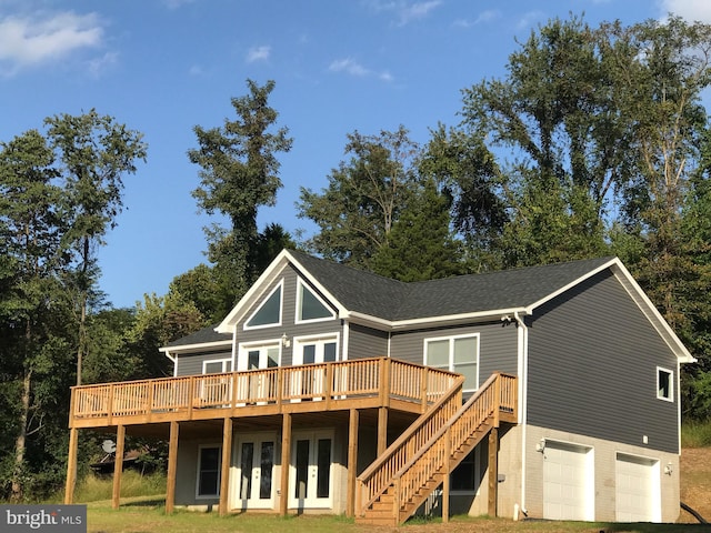 back of house with an attached garage, french doors, roof with shingles, and a deck