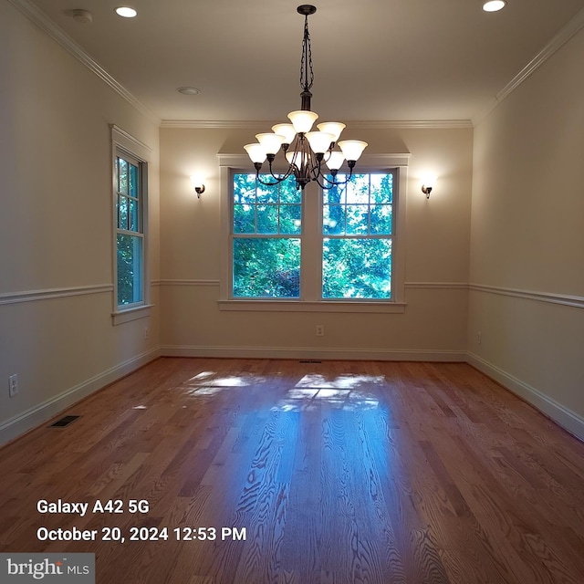 unfurnished dining area with ornamental molding, a chandelier, and wood-type flooring