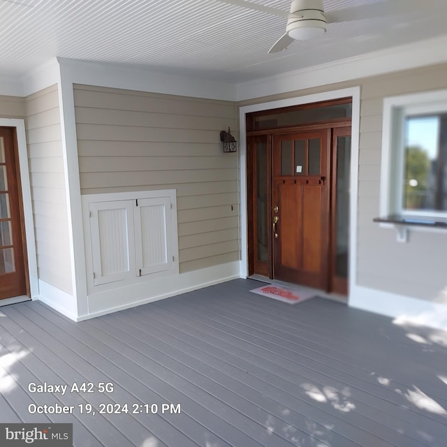 entrance to property with ceiling fan and a deck