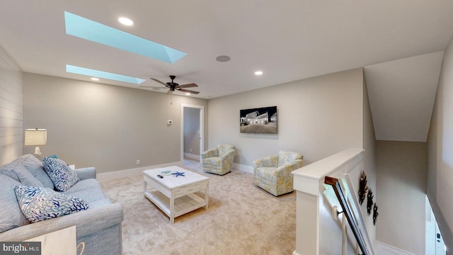 carpeted living room with ceiling fan and a skylight