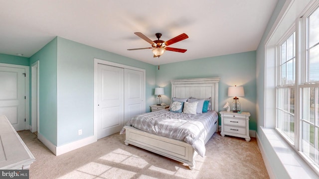 bedroom featuring ceiling fan, a closet, light colored carpet, and multiple windows