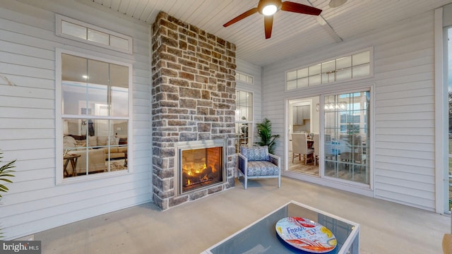 interior space featuring a stone fireplace, ceiling fan, and wood ceiling