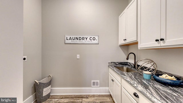 washroom with hookup for an electric dryer, cabinets, sink, and dark wood-type flooring