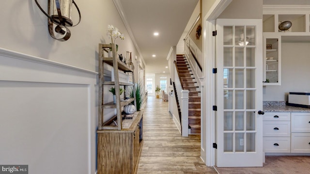 hall with light wood-type flooring and ornamental molding