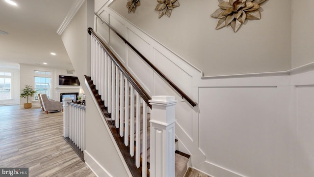 stairway featuring wood-type flooring and crown molding