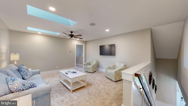 carpeted living room featuring ceiling fan and a skylight