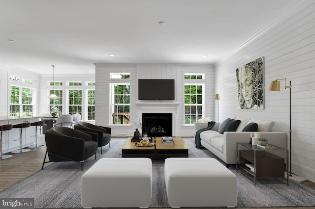 living room with wood walls, wood-type flooring, and ornamental molding