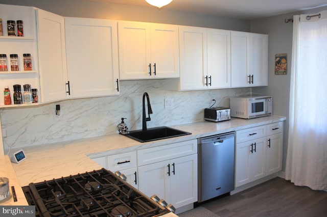 kitchen with light stone counters, dark wood-type flooring, sink, dishwasher, and white cabinetry