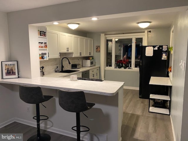 kitchen featuring kitchen peninsula, a kitchen breakfast bar, white cabinetry, and sink