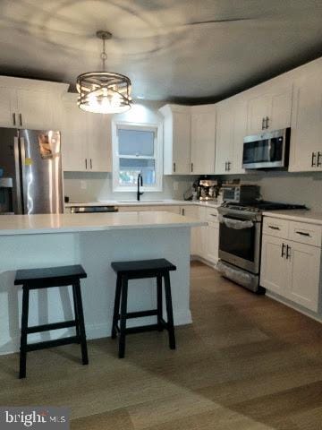 kitchen with sink, pendant lighting, white cabinetry, and stainless steel appliances