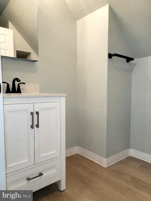 interior space featuring vanity, lofted ceiling, and wood-type flooring