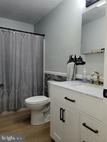 bathroom with vanity, hardwood / wood-style floors, a shower with shower curtain, and toilet