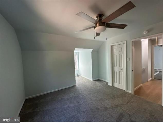 bonus room with dark carpet, vaulted ceiling, and ceiling fan