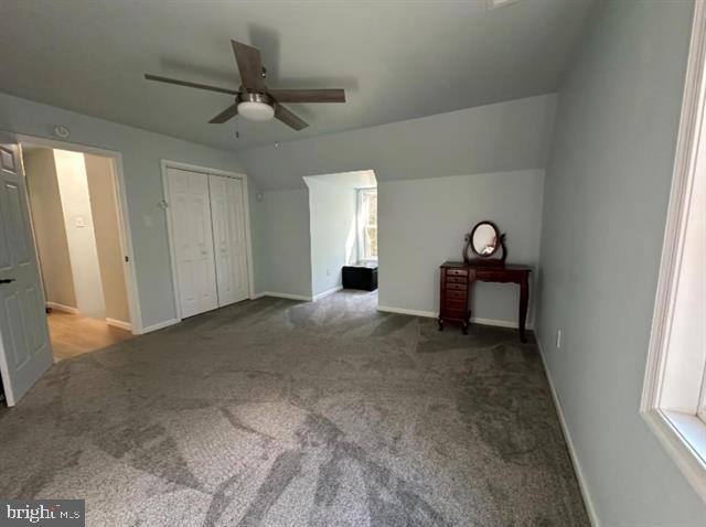 unfurnished bedroom featuring vaulted ceiling, light colored carpet, a closet, and ceiling fan