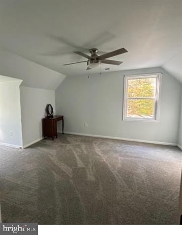 bonus room with vaulted ceiling, dark colored carpet, and ceiling fan